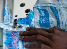 Woman sewing bags from discarded plastic material. By Tomas Prochazka. From Wikimedia Commons.